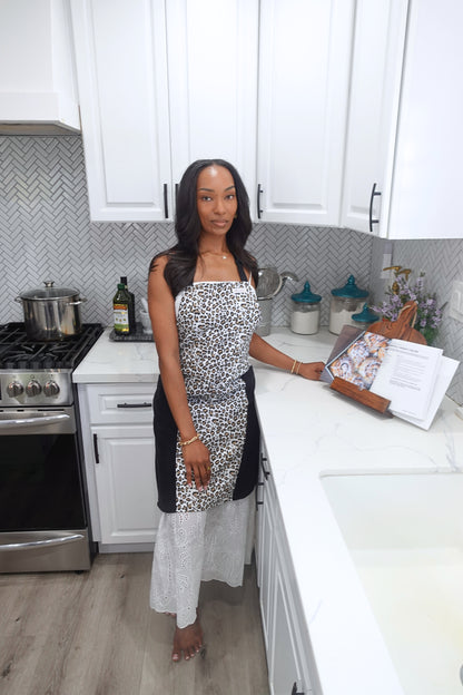 Woman wearing Safari leopard print baking apron with black microfiber towel panels in a kitchen